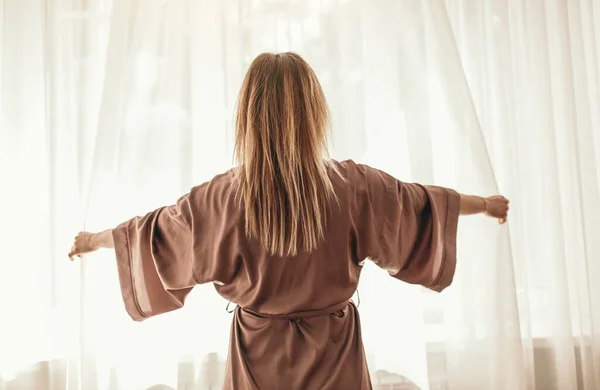Mulher acordando e abrindo cortinas — Fotografia de Stock