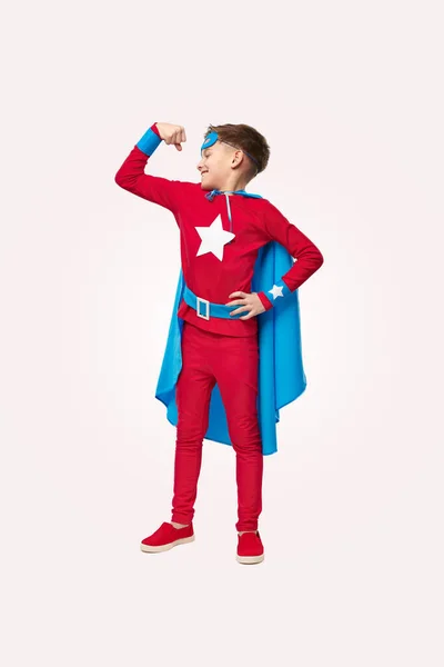 Feliz chico superhéroe mostrando bíceps en el estudio — Foto de Stock