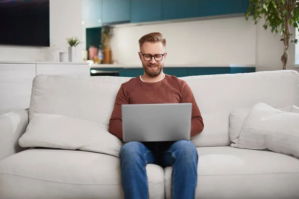 Uśmiechnięty samozatrudniony mężczyzna pracujący na laptopie w domu — Zdjęcie stockowe