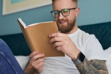 Evde kitap okuyan neşeli bir adam.