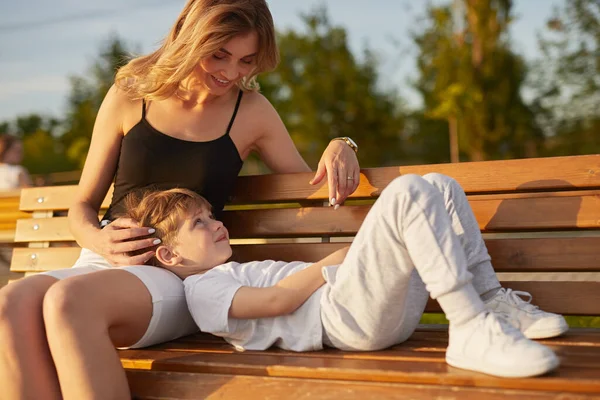 妈妈在公园的长椅上爱抚儿子 — 图库照片