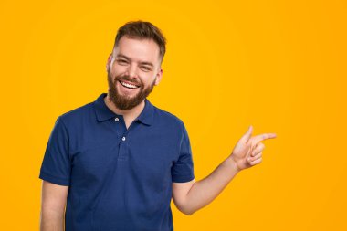 Gülümseyen sakallı adam stüdyoyu işaret ediyor.