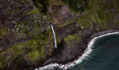 Kayalık dağlardan dalgalı denize akan hızlı şelale.