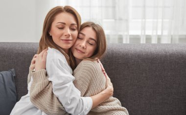 Mutlu bir anne ve kız evde sarılıyor.