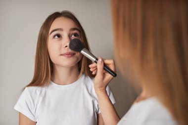 Kırsal anne kızının makyaj yapmasına yardım ediyor.