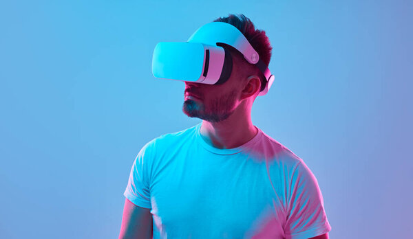 Man in VR headset experiencing virtual reality in studio with neon lights