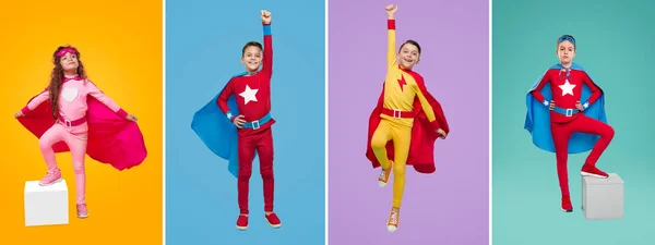Cheerful kids in superhero costumes in studio