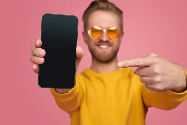 Hombre feliz apuntando al teléfono inteligente con pantalla negra — Foto de Stock
