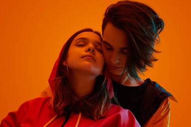 Turuncu neon ışığın altında sarılan genç çift