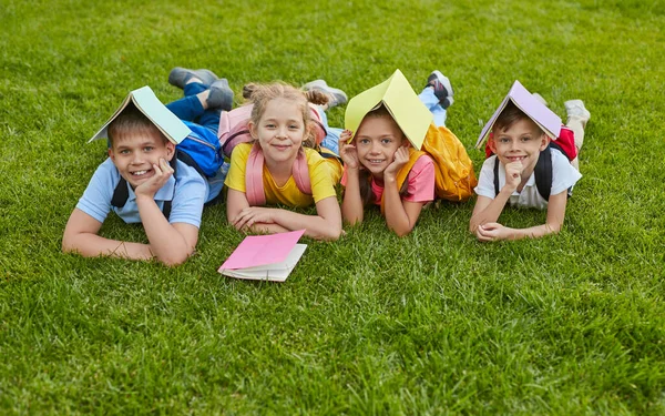 Boys and girls with notepads resting after school — Stock Photo, Image