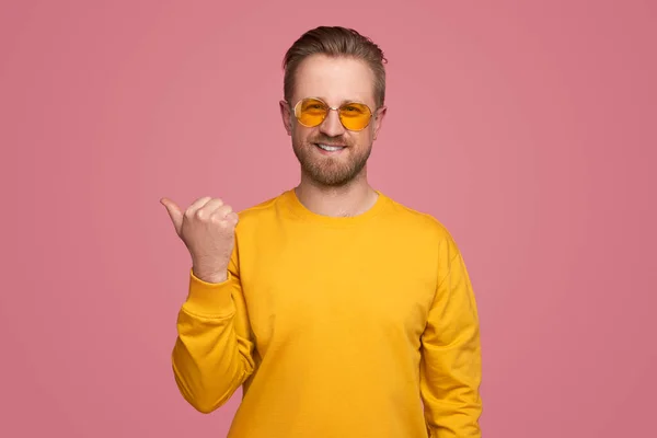 Stylish man pointing aside with thumb — Stock Photo, Image