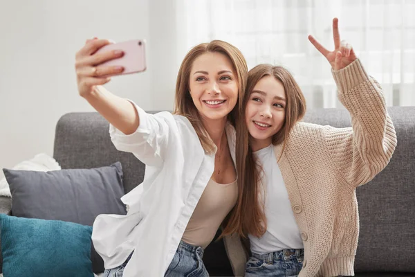 Lachende moeder en dochter nemen selfie op smartphone op de bank — Stockfoto