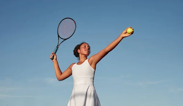 Černá sportovkyně hraje tenis proti modré obloze — Stock fotografie