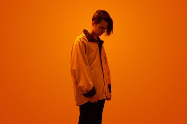 Neon turuncu ışık altında şık bir genç.