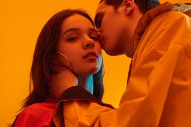 Genç kız arkadaşını neon ışığın altında öpüyor.