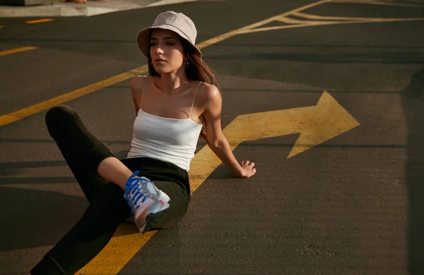 Trendy woman sitting on asphalt ground — Stock Photo, Image