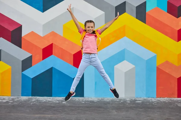 Positieve tiener student springen tegen heldere muur — Stockfoto