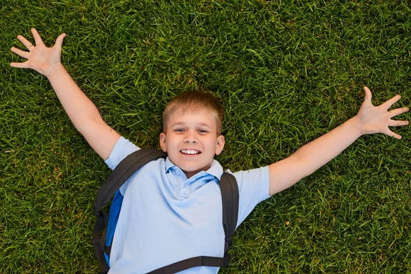 Веселый школьник лежит на траве — стоковое фото