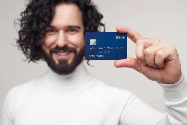 Χαμογελώντας άνθρωπος δείχνει πιστωτική κάρτα στο χέρι στο στούντιο — Φωτογραφία Αρχείου