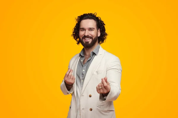 Homem barbudo feliz gesticulando dinheiro ou salário no fundo amarelo — Fotografia de Stock