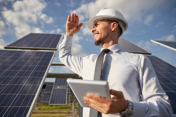 Felice uomo d'affari in hardhat in piedi con tablet tra i pannelli solari — Foto Stock