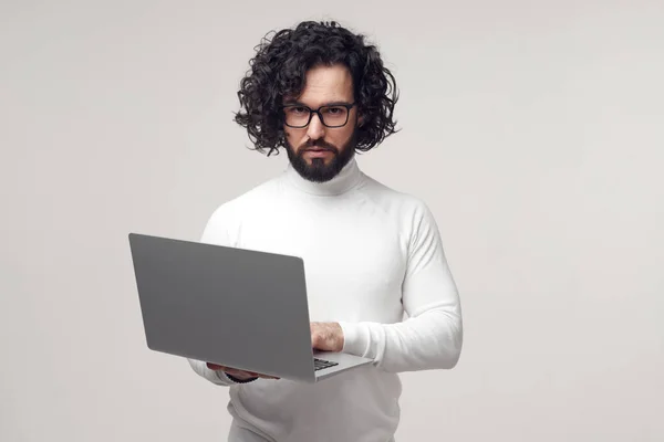 Szigorú férfi szemüvegben gépel laptopon a stúdióban — Stock Fotó