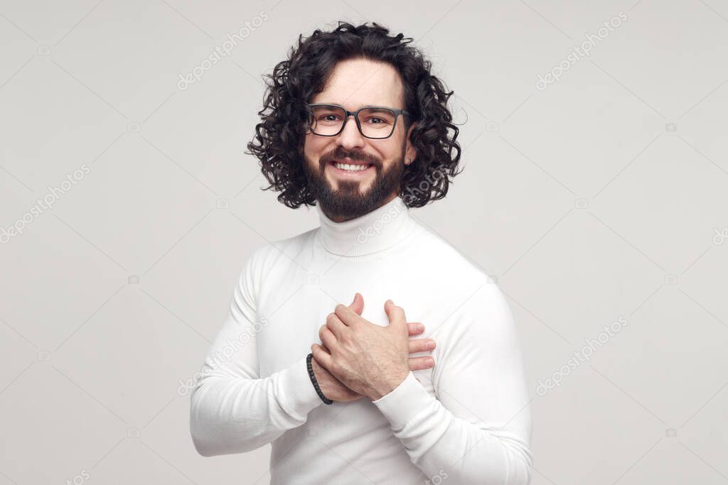 Grateful happy man keeping hand on chest in studio