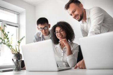 Dizüstü bilgisayarla çalışan neşeli meslektaşlar.