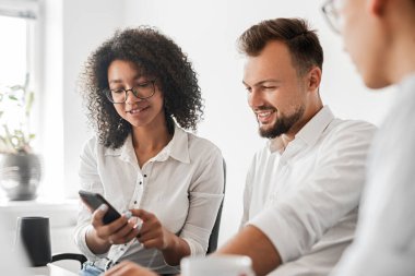 Neşeli siyah kadın akıllı telefona bakıyor.