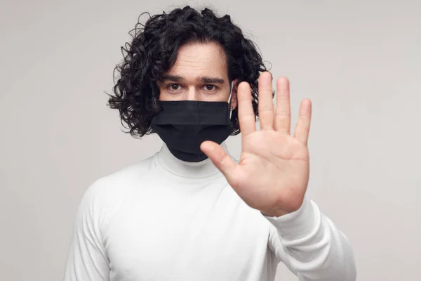 Людина в захисній масці, що показує стоп жест з долонею — стокове фото