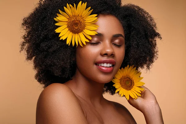 Glad African American female decorating hair with flowers — Stock Photo, Image