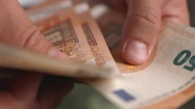 50 avroluk banknotları sayan bir elin yakın çekimi. Erkek eller Avrupa parasını yavaş çekimde sayar