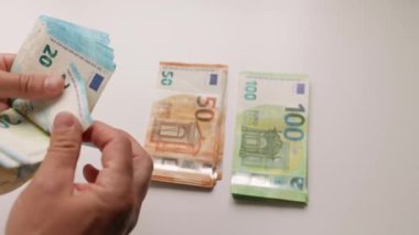 Yakından bir erkek eli bir sürü avro banknotu sayıyor. Tanımlanamayan adam yatırım için para hazırlıyor. Borç konsepti için ödeme