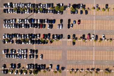 Boş park yeri olan hava manzaralı bir yer. Alışveriş merkezinin önünde park etmiş bir sürü araç var..