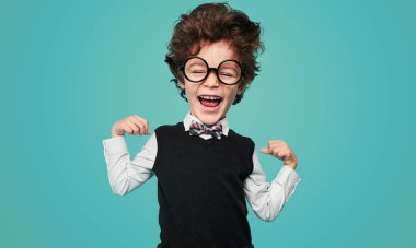 Okul üniformalı şirin küçük inek ve koca kafalı gözlüklü turkuaz arka planda yapılan çalışmalar sırasında bisepsleri gösterip gülüyor.