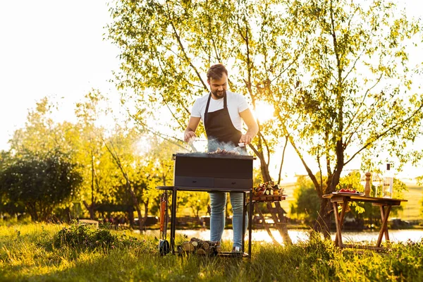 Corpo Inteiro Chef Masculino Avental Sorrindo Grelhando Salsichas Perto Árvore — Fotografia de Stock