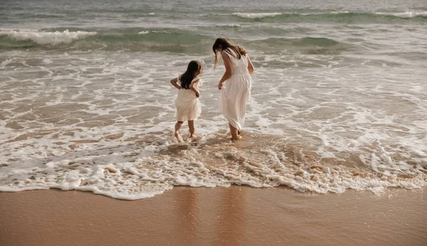 Back View Mother Daughter White Dresses Walking Foamy Sea Waves — 스톡 사진