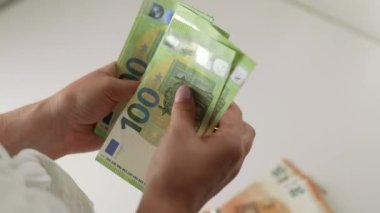 Unrecognizable woman counting cash salary of one hundred euro bills. Slow motion 4k video of female counting european currency