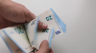 A close up shot of hand counting 20 euros banknotes. Male hands count European money in a pile of money