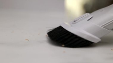 Closeup shot of vacuum cleaner cleaning crumbs dirt on kitchen table. Housekeeping concept