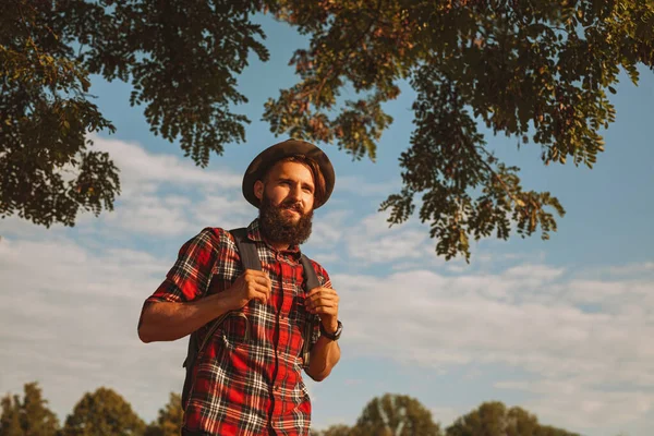 Bearded Man Checkered Shirt Hat Backpack Walking Lush Tree Branches — Fotografia de Stock