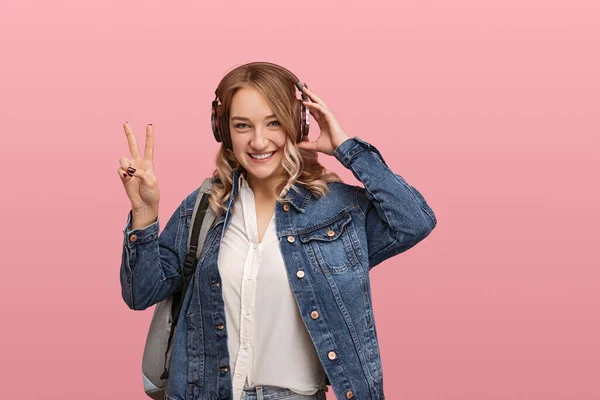 Happy Young Woman Denim Jacket Backpack Adjusting Wireless Headphones Gesturing — Stok fotoğraf