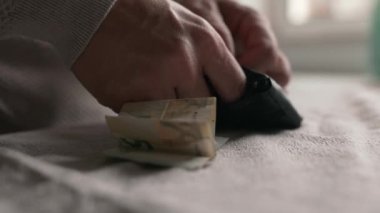 Miserable man takes the last money out of the wallet onto the table. Poor person having finance issues. Poverty and savings concept