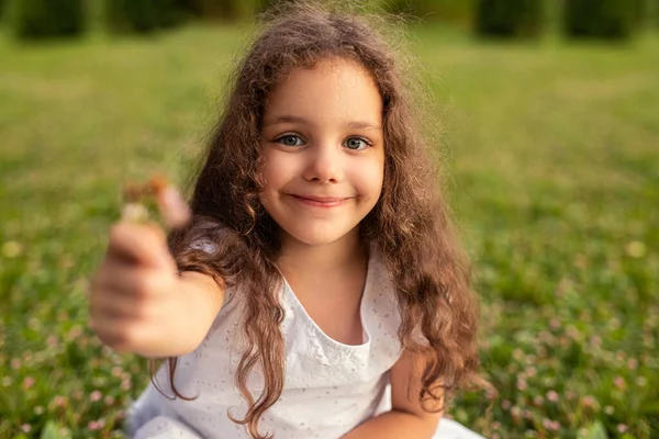 Чарівна Маленька Дівчинка Білій Сукні Розтягнута Рука Квіткою Біля Камери — стокове фото