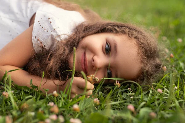 Menina Alegre Com Cabelos Cacheados Relaxando Grama Olhando Para Flores — Fotografia de Stock