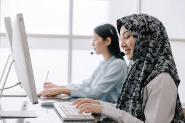 Sekreter operatörü danışman yardımı için kulaklık ve mikrofon takar, çağrı merkezi personeli gülümseyen ve mutlu bir şekilde müşterilere tavsiye ve yardım eder