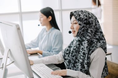 Sekreter operatörü danışman yardımı için kulaklık ve mikrofon takar, çağrı merkezi personeli gülümseyen ve mutlu bir şekilde müşterilere tavsiye ve yardım eder