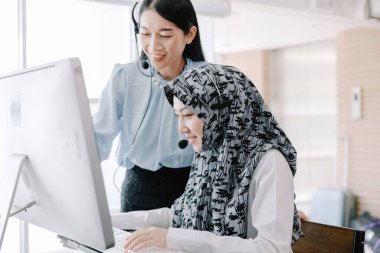 Sekreter operatörü danışman yardımı için kulaklık ve mikrofon takar, çağrı merkezi personeli gülümseyen ve mutlu bir şekilde müşterilere tavsiye ve yardım eder