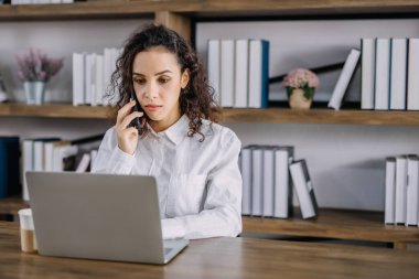 Bir iş kadını evinde bilgisayarını ve kahve fincanını kullanan bir müşteriyle telefonda konuşuyor. Ev konseptinden çalışıyor..