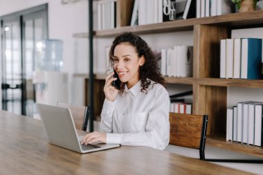 Genç iş kadını, ev konseptinden mutlu müşterilerle telefonda konuşuyor.